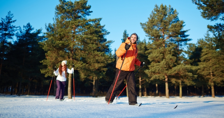 Two skiers navigate a snowy trail in Whitefish, Montana, emphasizing the joy of cross country skiing in winter.