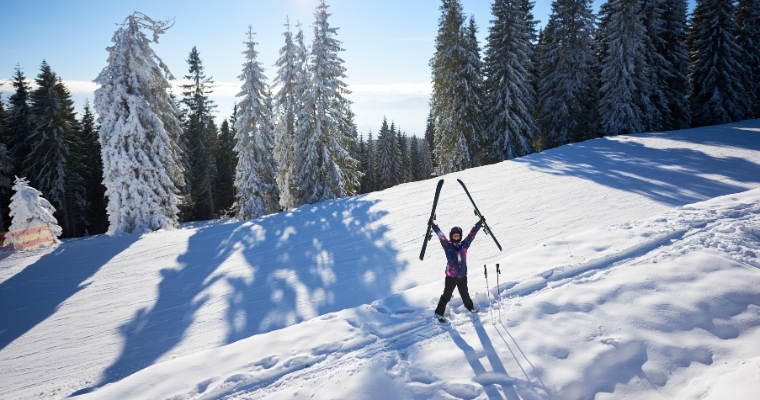 A skier on a snow-covered hill, with luxury homes in Whitefish, Montana, and the majestic Big Mountain in the distance.