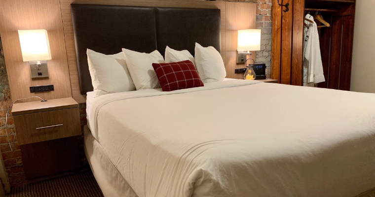 Hotel room featuring a bed and two lamps, showcasing the cozy ambiance of Grouse Mountain Lodge in Whitefish, Montana.