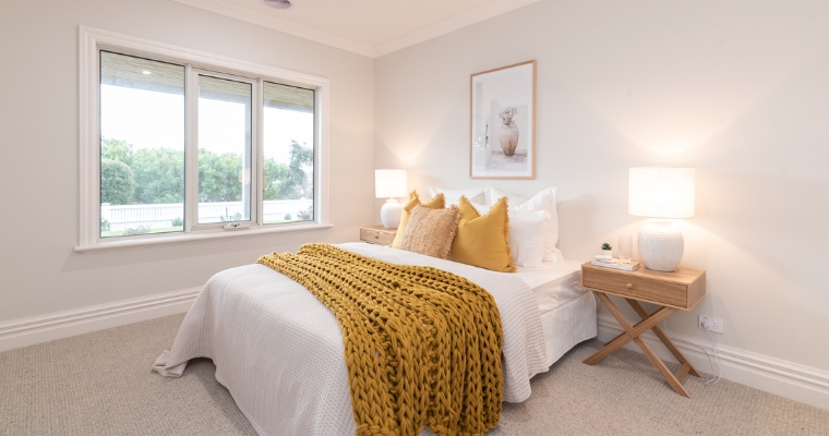 Cozy bedroom featuring a white bed adorned with a bright yellow blanket at Hampton Inn & Suites in Whitefish, Montana.
