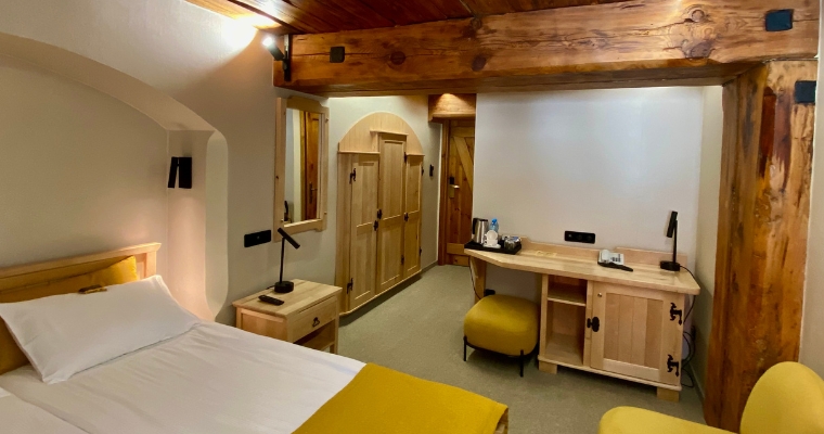 Hotel room featuring a bed, desk, and wooden walls at Kandahar Lodge in Whitefish, Montana.
