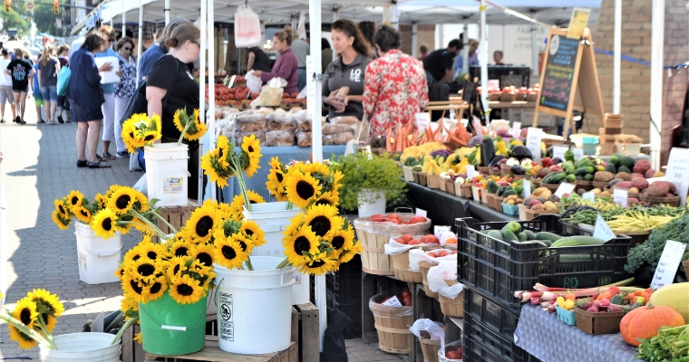 A vibrant farmer's market featuring sunflowers and fresh produce, showcasing local goods in Whitefish, Downtown Farmers Market.