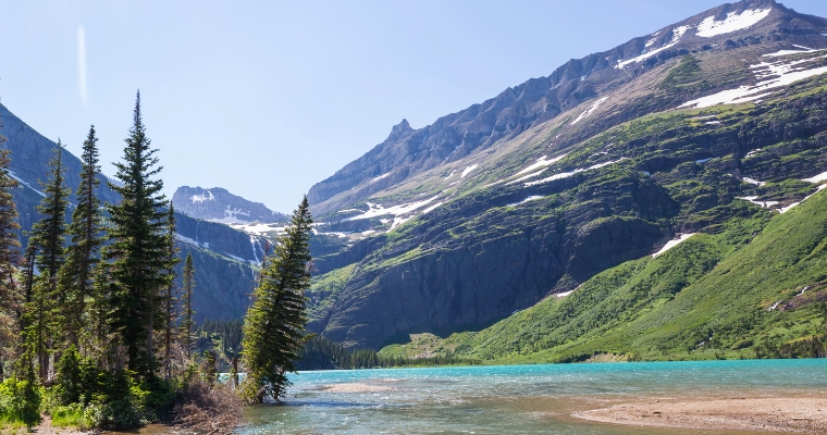 A serene mountain lake framed by lush trees and towering mountains, showcasing the stunning natural beauty of Whitefish Events.