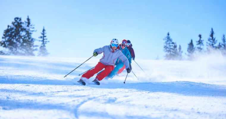 A group of people ski down a snowy slope at Big Mountain Summit, highlighting the winter landscape of Whitefish, Montana.