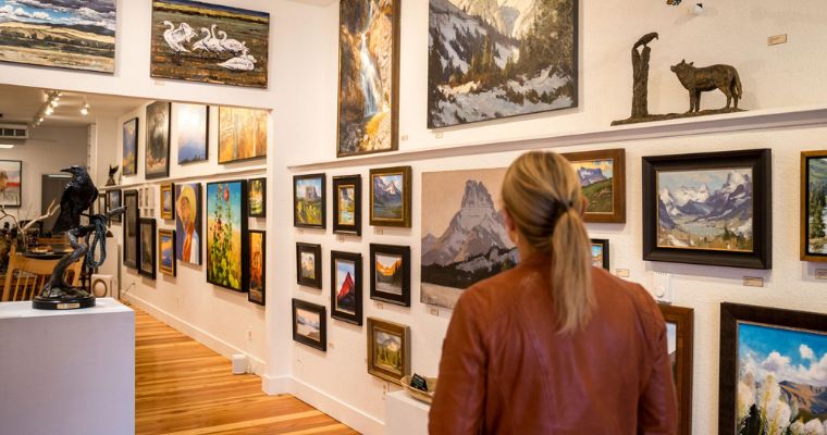 A woman admires art in a gallery in downtown Whitefish, Montana, highlighting the vibrant cultural scene of the area.