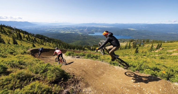 Bikers descend a mountain trail, showcasing the exhilarating mountain biking experience in Whitefish, Montana.