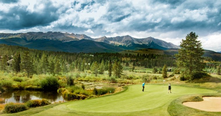 Whitefish Lake Golf Club showcases a beautiful golf course with impressive mountains rising in the background.