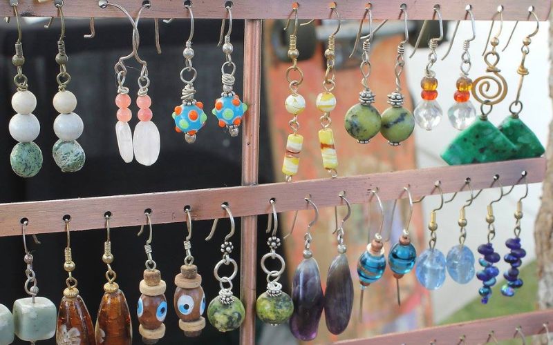 A vibrant collection of crafts earrings elegantly arranged on a wall rack, featured at the Whitefish Arts Festival celebration.