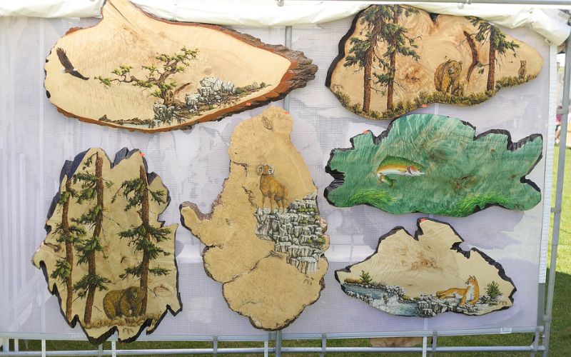 Various intricately designed wooden pieces displayed at the Whitefish Arts Festival, showcasing talent and craftsmanship.