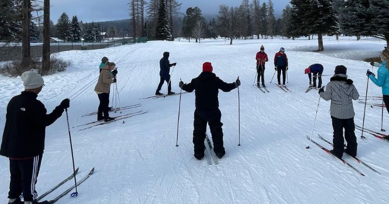 A group of skiers navigating through the snowy landscape at Glacier Nordic Center in Whitefish, Montana.