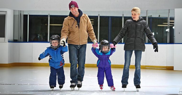 A family enjoys ice skating together at Stumptown Ice Den in Whitefish, Montana, creating joyful winter memories.