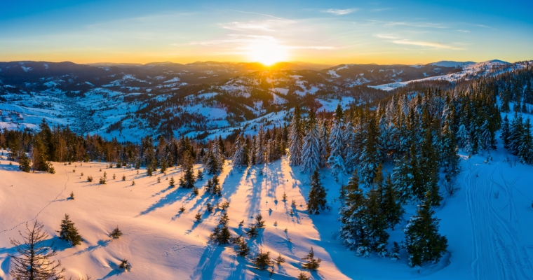 A stunning sunset casts warm hues over snowy peaks at Big Mountain Summit in Whitefish, Montana.