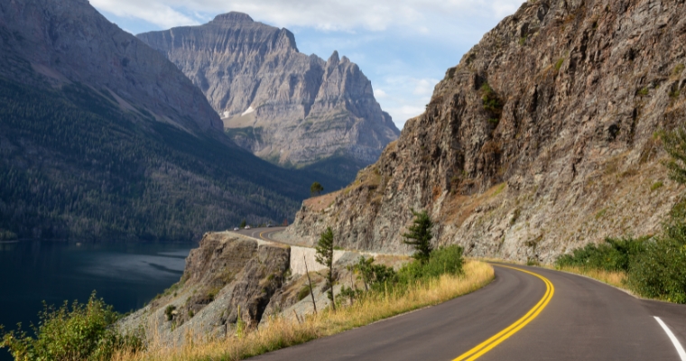 Scenic road winding through mountains, showcasing the beauty of Going-to-the-Sun Road in Whitefish, Montana.