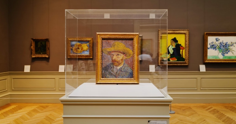 A painting of a man wearing a straw hat displayed in a glass case at a local art gallery in Whitefish, Montana.