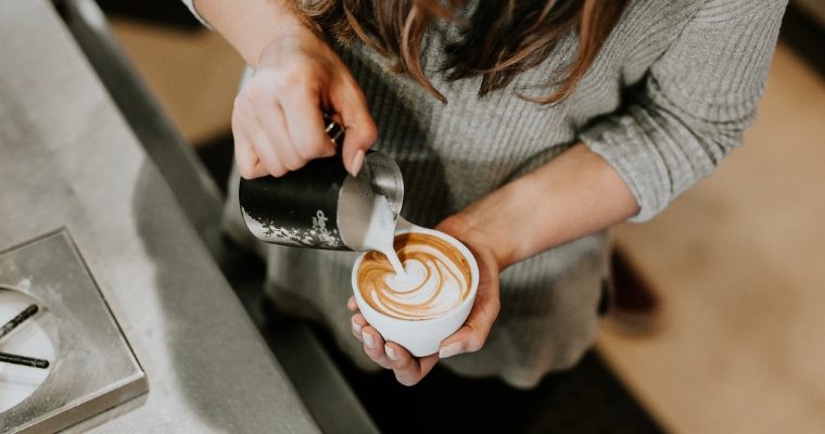 A woman pours coffee into a cup, highlighting the local coffee culture in Whitefish, Montana.