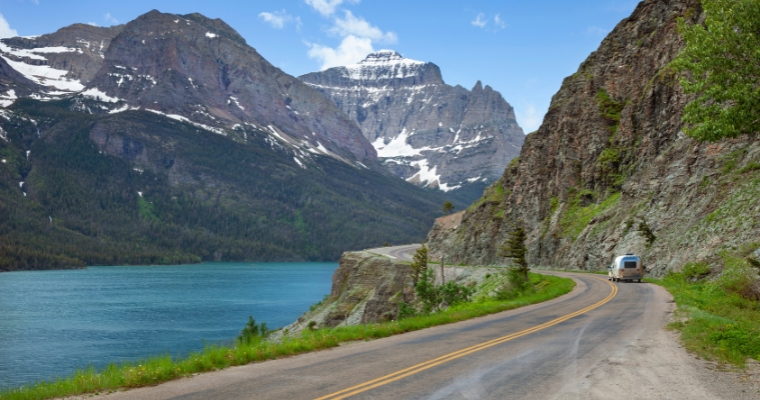Scenic view of a road leading to a mountain, with a tranquil lake in the foreground, showcasing Whitefish, Montana.