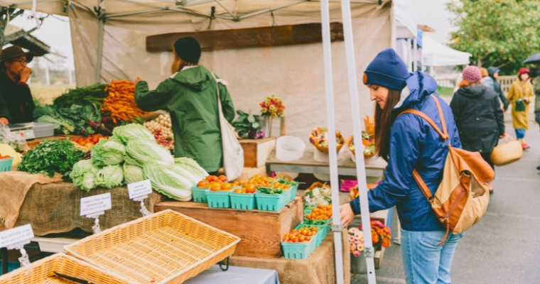 People browsing and shopping at the Whitefish Farmers Market, showcasing local produce and artisanal goods.