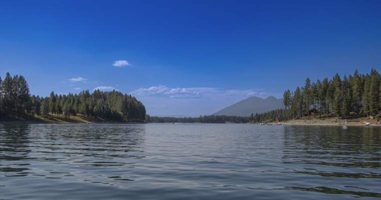 Scenic view of Whitefish Lake, surrounded by lush trees and majestic mountains in Whitefish, Montana.