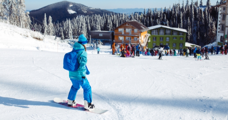 A person on a snowboard stands on a snowy slope, highlighting the winter activities at Whitefish Mountain Resort in Montana.