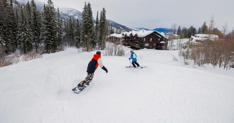 Two snowboarders glide down a snowy slope, showcasing the thrill of outdoor activity at Whitefish Mountain Resort.