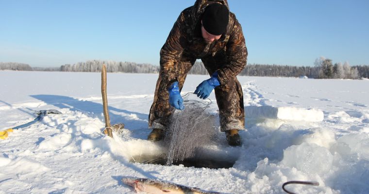 A man on the ice of Whitefish Lake proudly displays a fish, capturing the essence of winter fun at the Whitefish Winter Carnival.
