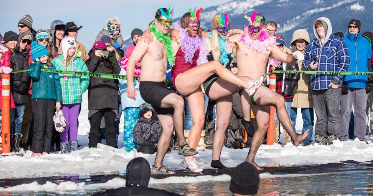 People gather on a frozen lake at the Penguin Plunge, highlighted the Whitefish Winter Carnival spirit.