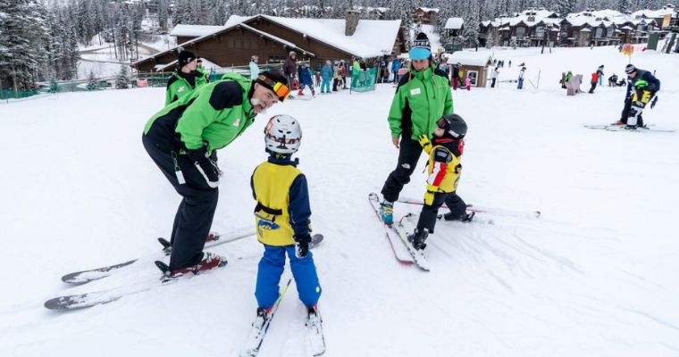 A group of children and their skiing instructors together in Whitefish, Montana, showcasing a joyful skiing lessons for all ages.