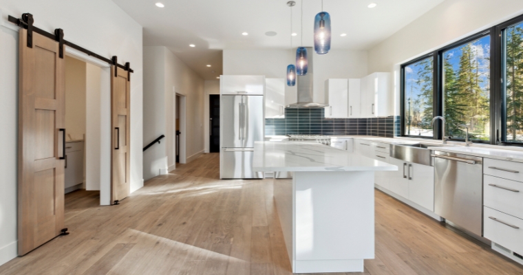 A luxurious kitchen featuring white cabinets and elegant wooden floors, showcasing modern design in a Whitefish home.