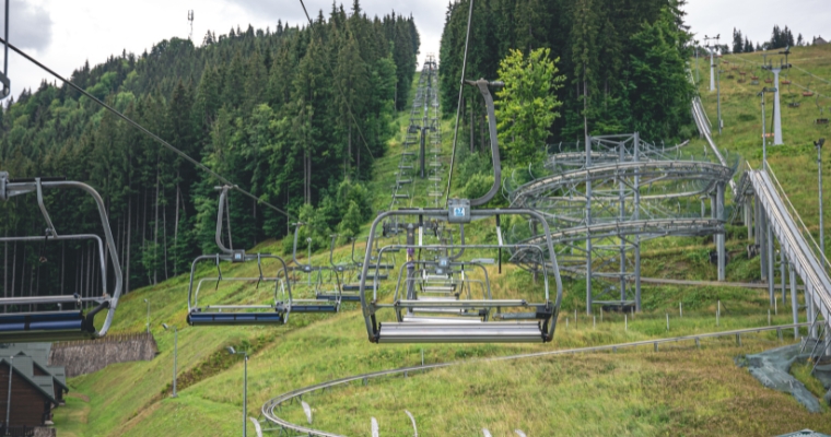A ski lift climbs a verdant mountain, illustrating the summer landscape of Whitefish during lift rides.