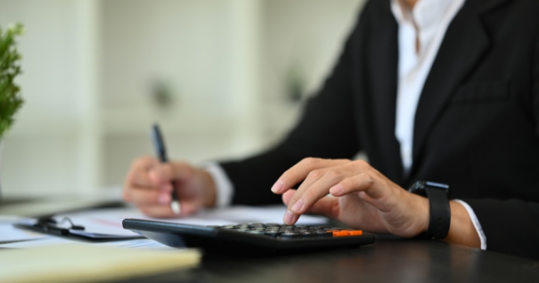 A professional in a suit operates a calculator to evaluate home building costs and budget factors in Whitefish.