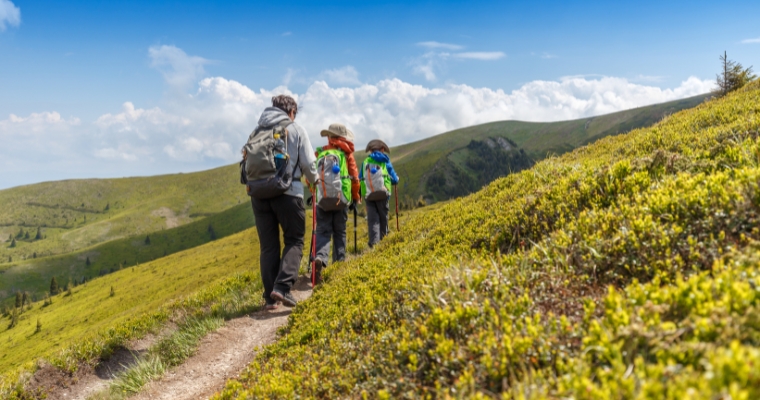 Three hikers on a mountain trail, showcasing the scenic beauty and outdoor lifestyle of Whitefish