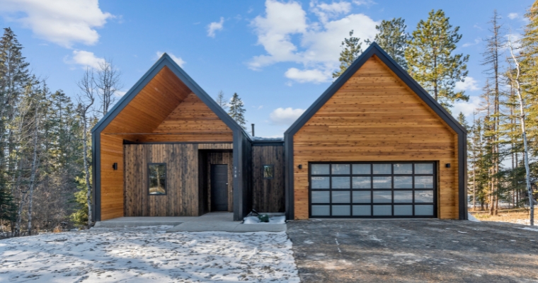 Stylish modern home with a wooden facade and dual garages, highlighting real estate trends in Whitefish.