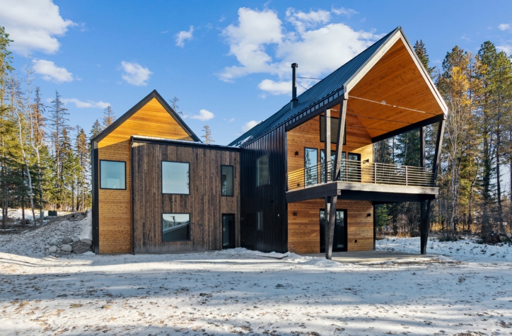 Modern home featuring wood siding and a sleek roof, designed by Custom Modern Home Builders in Whitefish.