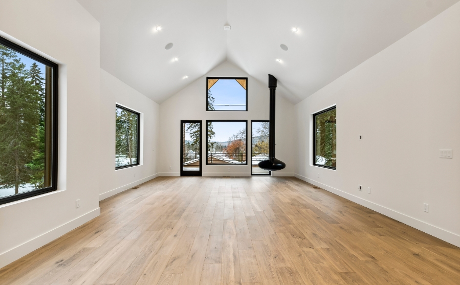 A spacious room featuring hardwood floors and large windows, designed by Custom Modern Home Builders in Whitefish.