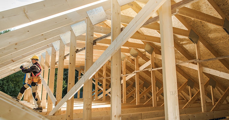 A man is working on a house roof, focusing on construction insights relevant to Whitefish, MT.
