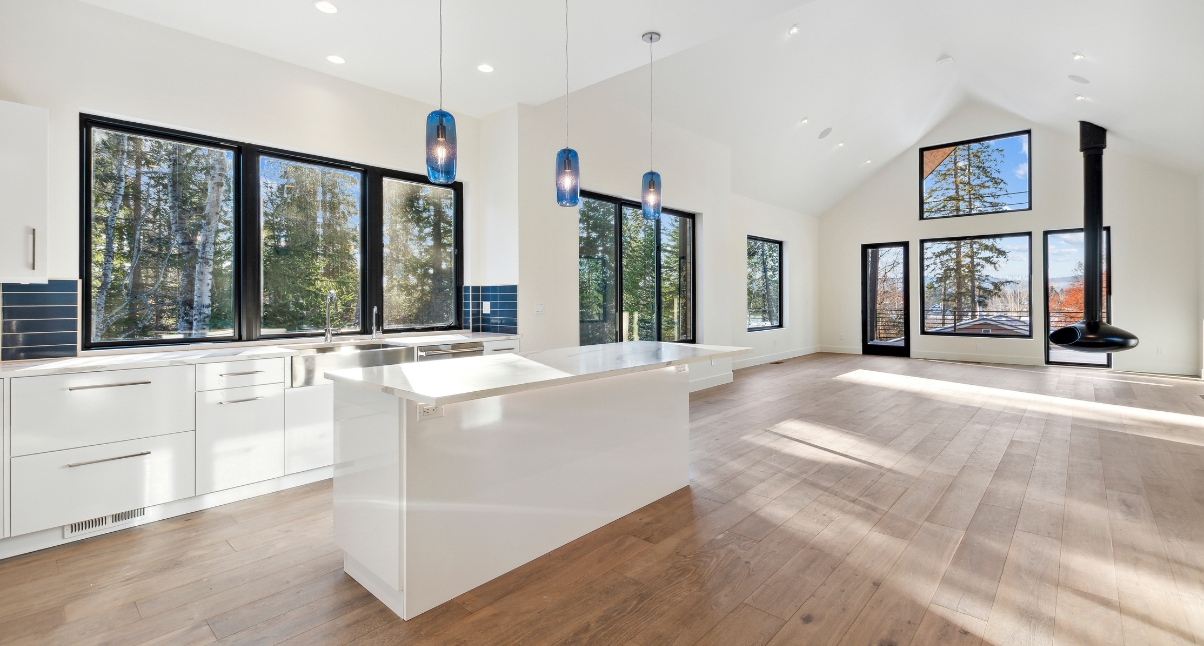 Spacious, bright kitchen and living area with white walls, and a modern suspended fireplace, highlighting custom modern homes whitefish with smart design.