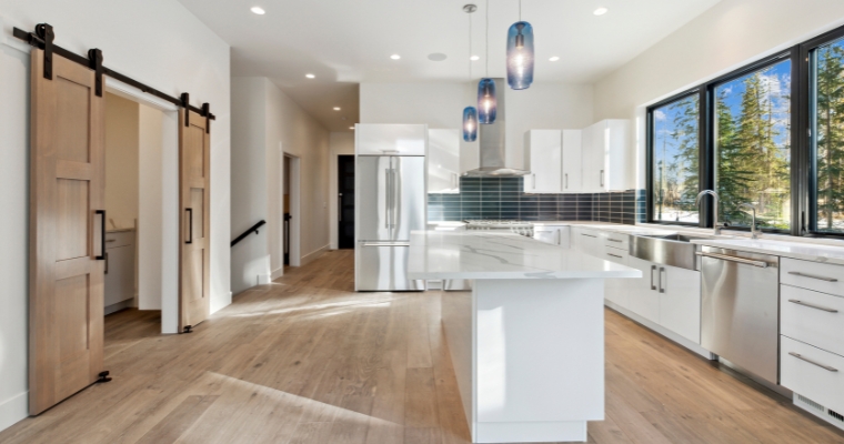 A modern kitchen featuring white cabinets and warm wooden floors, showcasing a stylish and inviting atmosphere.