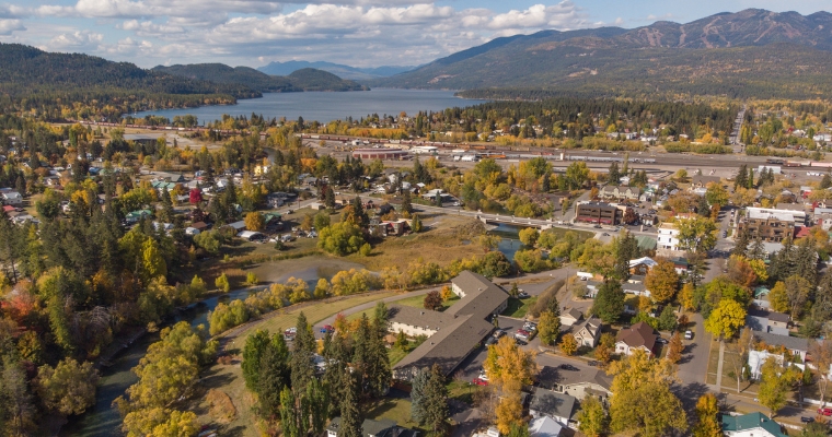 Aerial perspective of a town encircled by trees and mountains, illustrating the charm of Whitefish, Montana's real estate market.