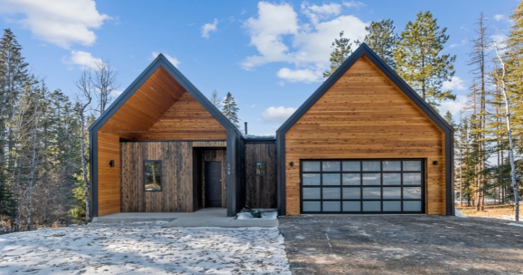 A modern cabin in Whitefish, Montana, featuring two garages and a spacious driveway, highlighting net-zero home design.