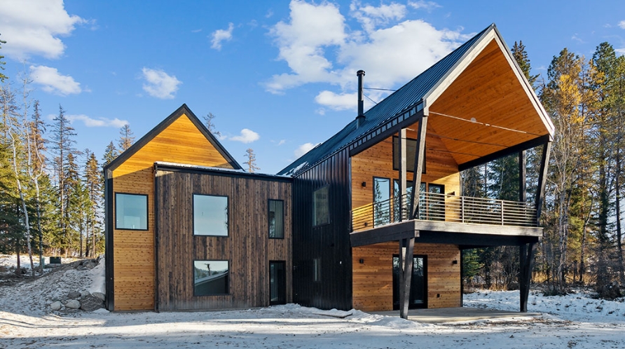 A modern cabin nestled in snowy woods, showcasing the craftsmanship of Montana Home Builders.