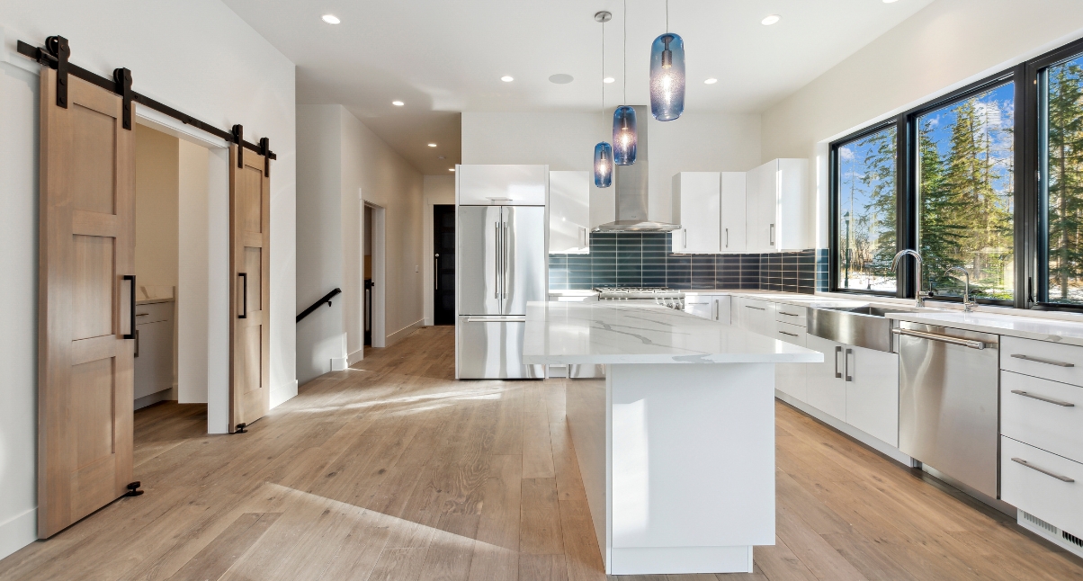 Stylish kitchen with white cabinets and wooden flooring, highlighting the innovative designs of Montana Home Builders.