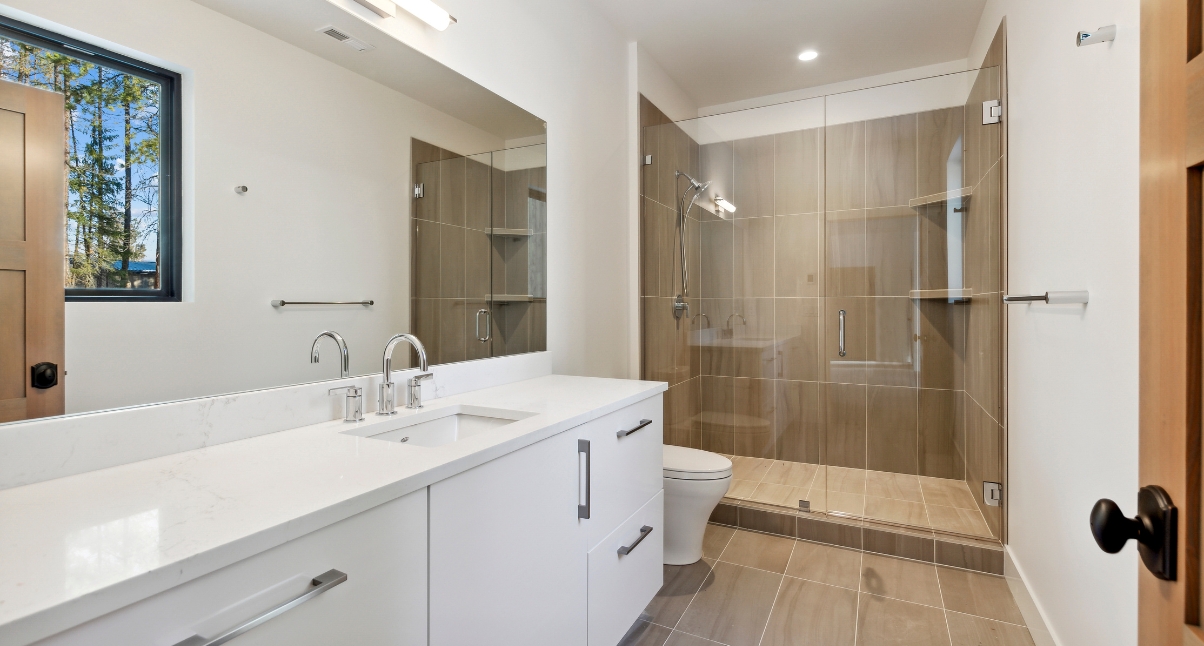 A bathroom featuring a walk-in shower and toilet, designed with sustainable materials by Montana Home Builders.