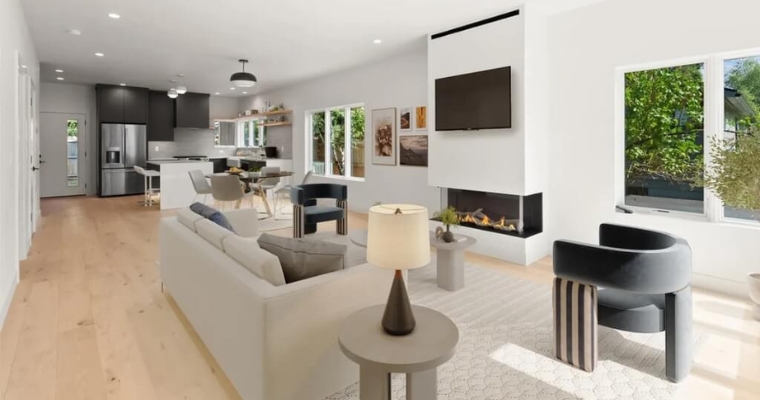 Stylish living room with a fireplace and kitchen area, exemplifying a modern aesthetic for a second home or vacation rental.