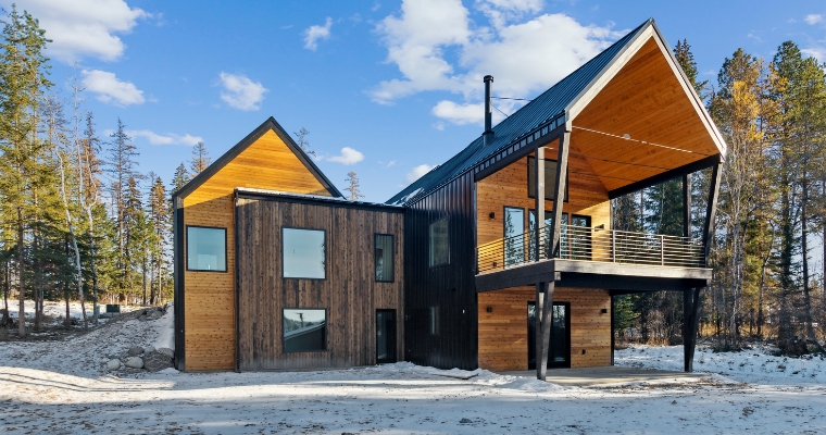 A modern cabin nestled in snowy woods, highlighting the theme of sustainability in Whitefish Second Home.