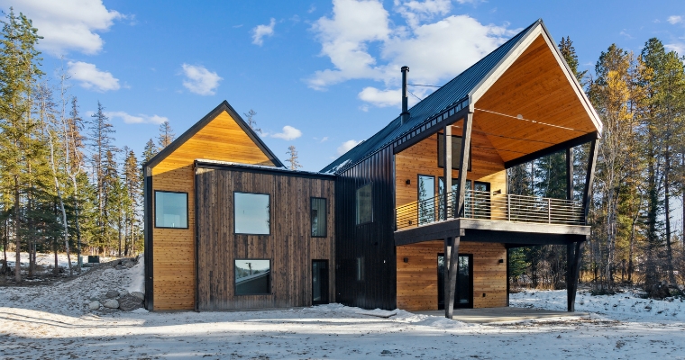 A contemporary cabin surrounded by snow-covered trees, representing the tranquil winter scenery in Whitefish.