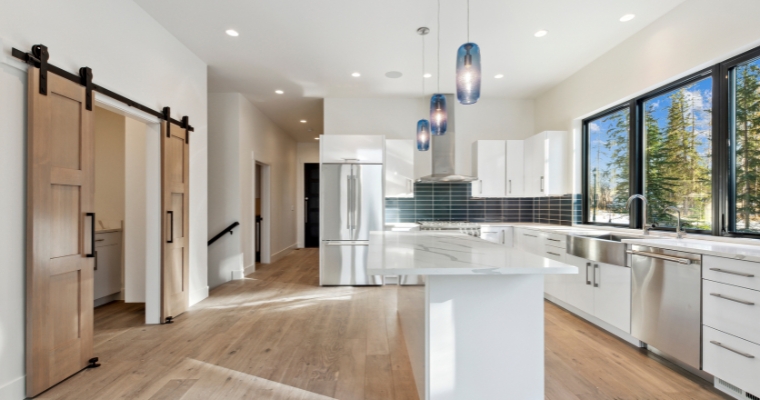 Stylish kitchen showcasing white cabinets and wooden floors, connected to Whitefish's cost of living and utility expenses.